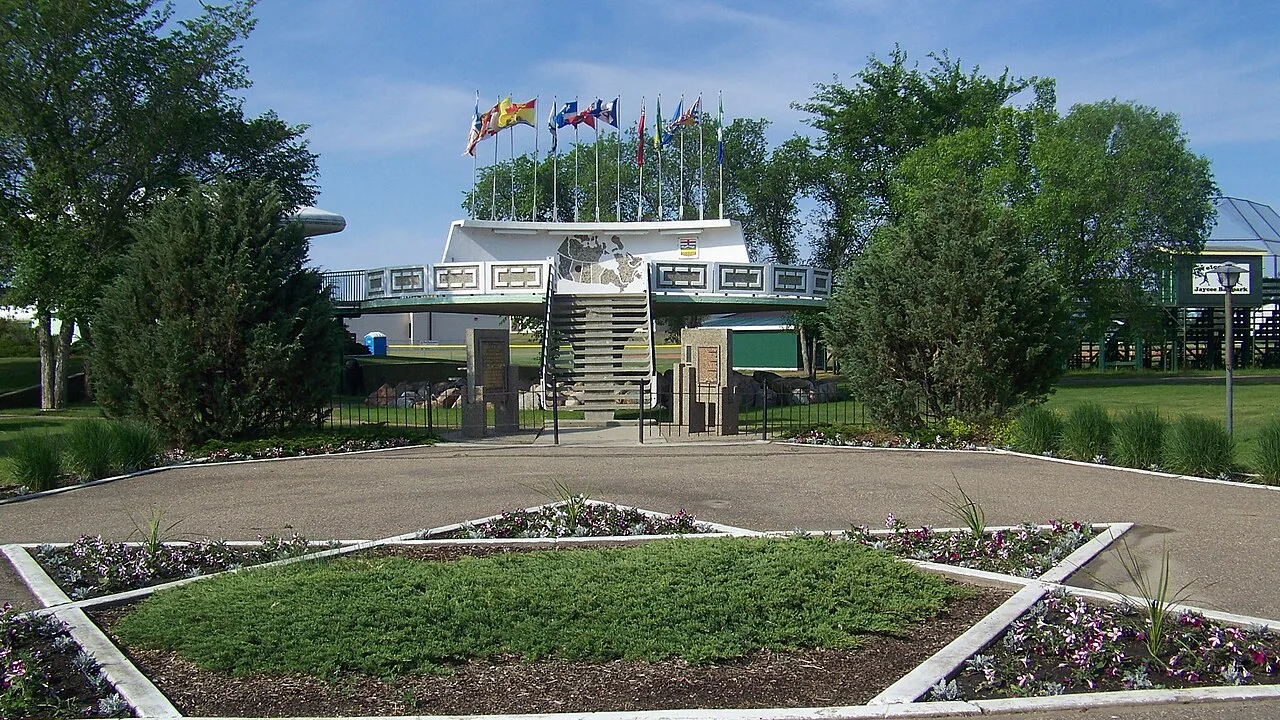 Photograph of the UFO landing pad in St. Paul, Alberta, a raised concrete platform with a staircase and flagpoles, seen from the plaza in front